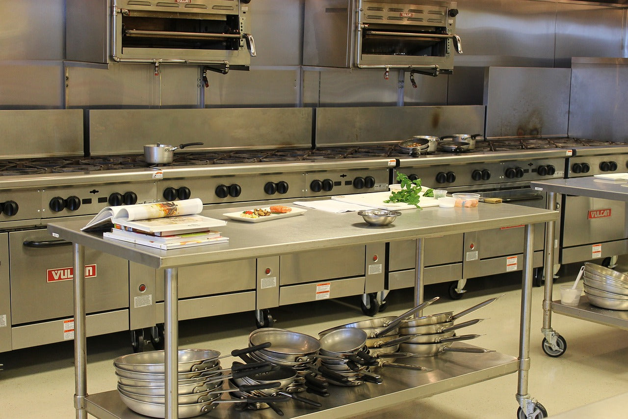  A prep table, range, and hood in a commercial kitchen